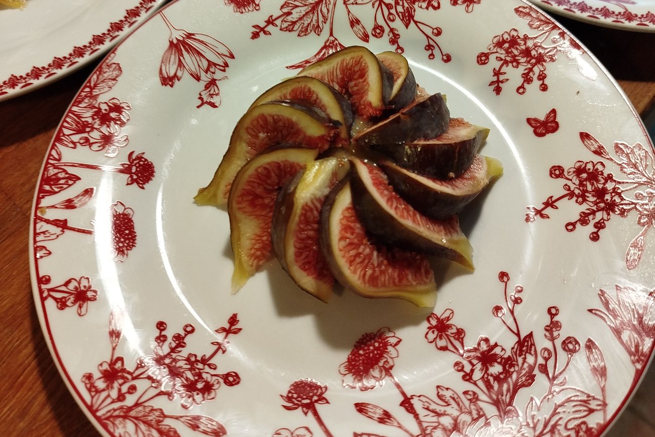 Figues fraîches disposées en rosace sur des assiettes de porcelaine fleurie rouge.
