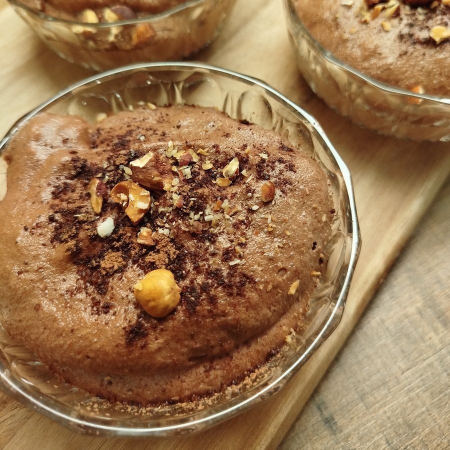 Mousses au chocolat parsemées de noisettes concassées, en coupes de verre ciselé.