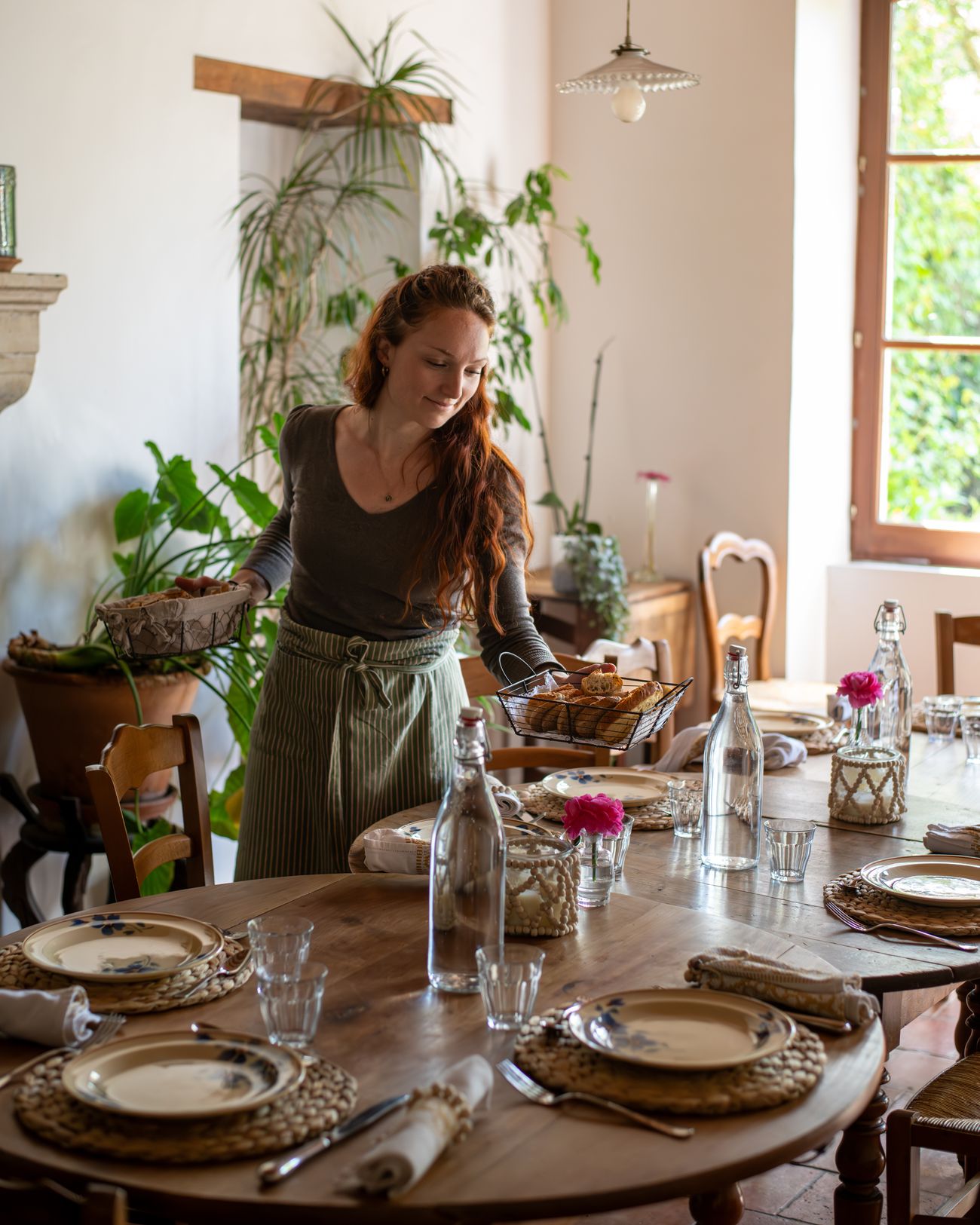 Laura Bridier dressant une table dans une salle à manger lumineuse.