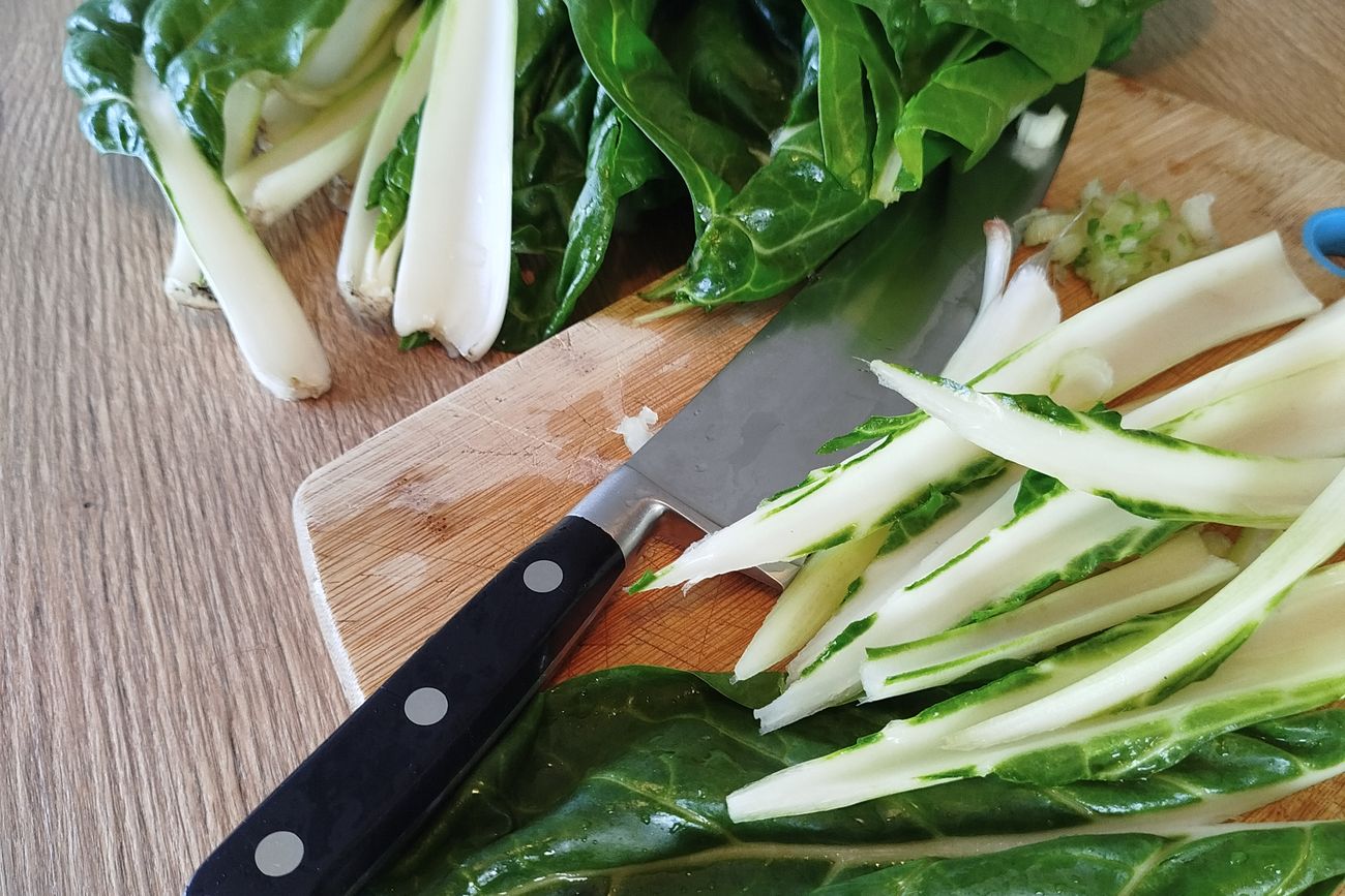 Blettes fraîches et couteau de cuisine sur une planche à découper.