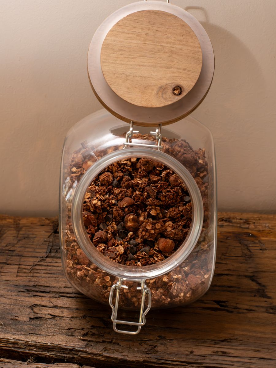 Bocal de granola maison posé sur une planche de bois brut.