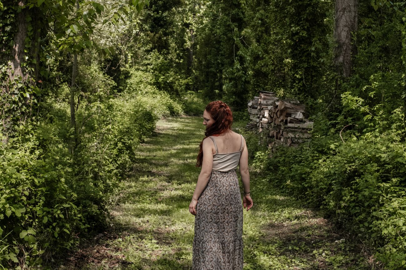 Laura Bridier marchant de dos dans une allée forestière.