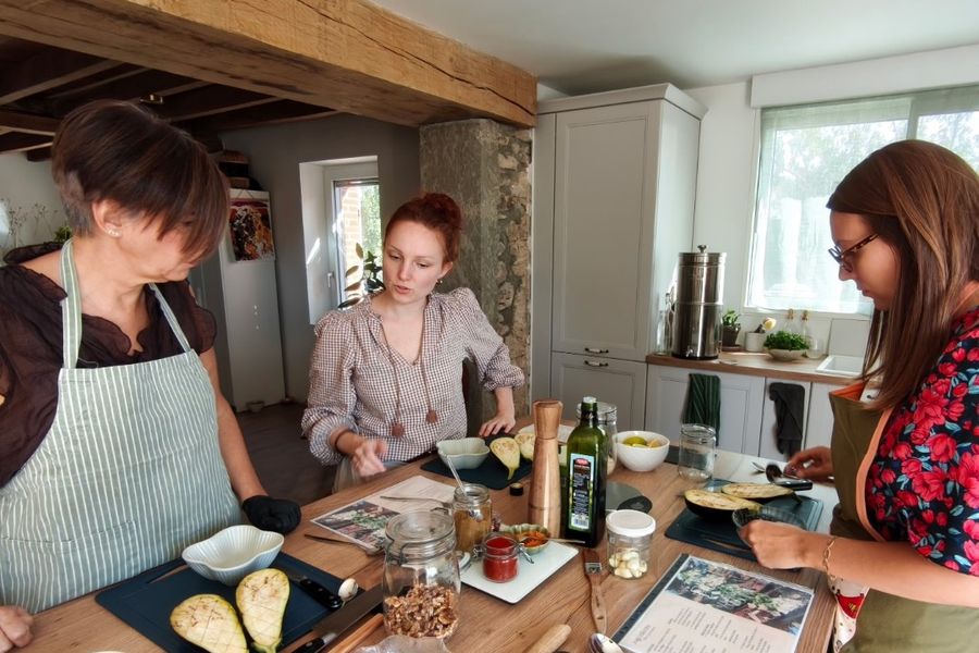 Atelier de cuisine : Laura Bridier et deux participantes préparent des aubergines autour du plan de travail.